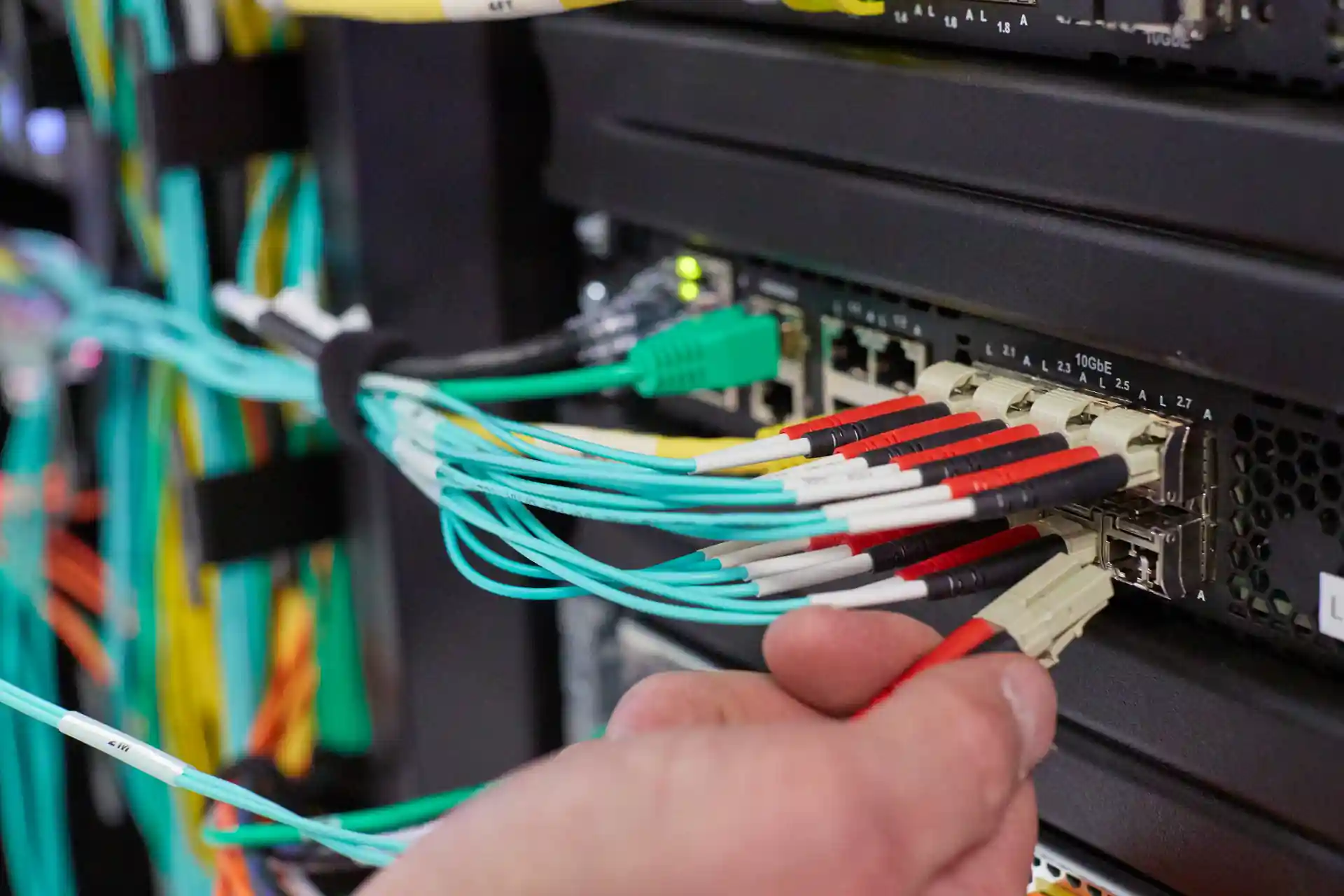 technician connecting fiber optic cables to data center network switch