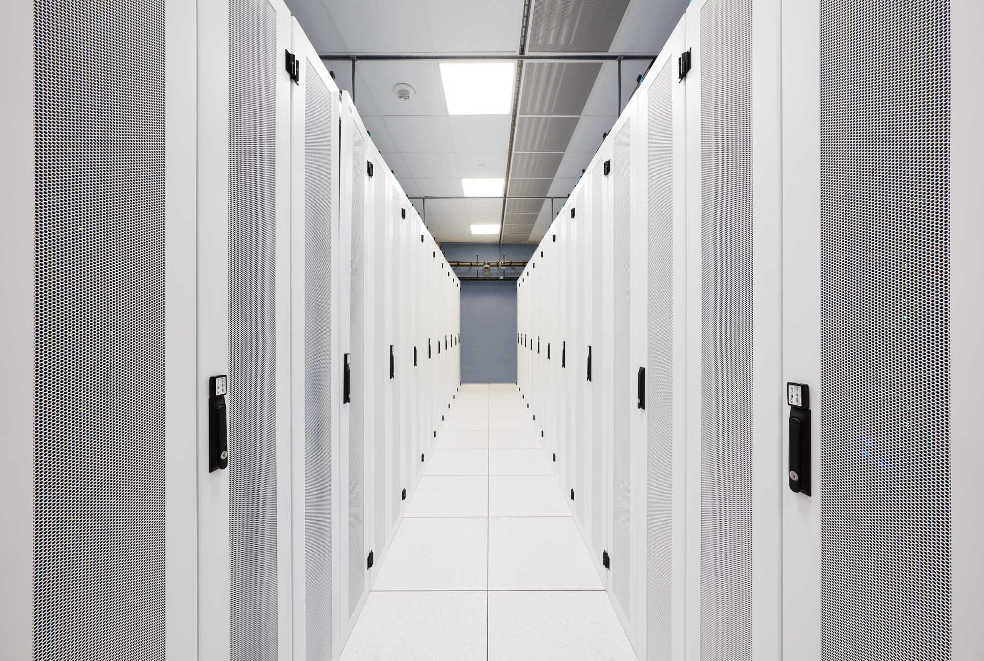 Bright data center aisle with rows of white server cabinets, used to illustrate professional data center photography services.
