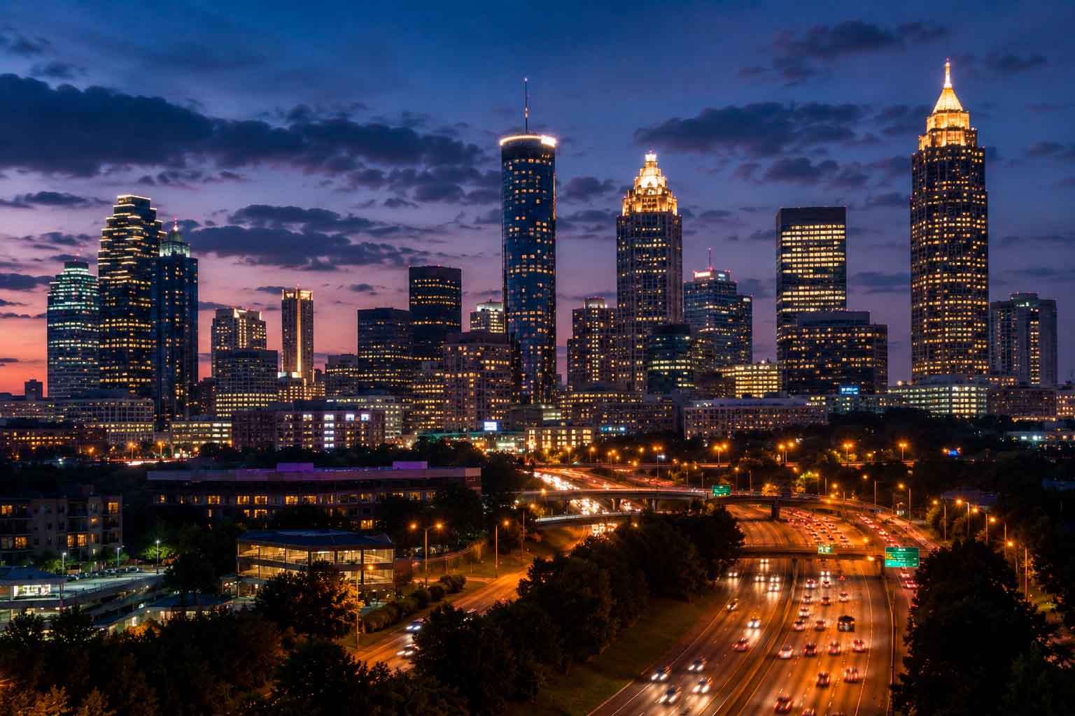 Atlanta skyline at dusk with illuminated towers, highways, and evening traffic, used as a regional context image for data center photographer services.