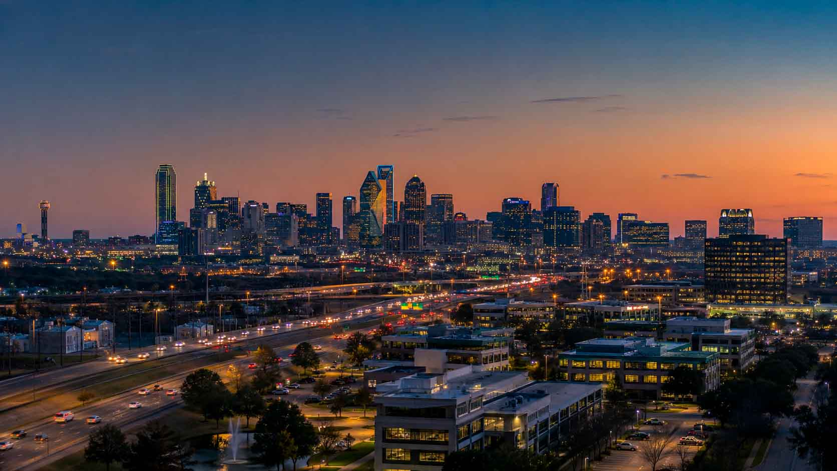 Dallas skyline at dusk with illuminated buildings, highways, and North Texas business infrastructure, used as a regional context image for data center photographer services.