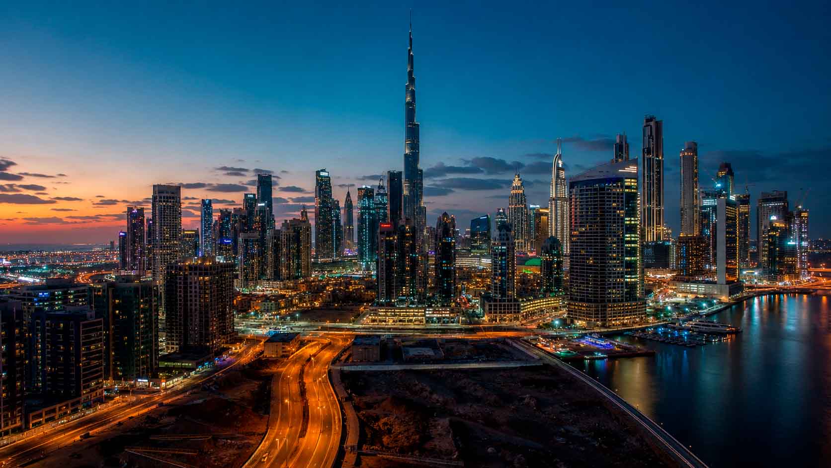 Dubai skyline at dusk with illuminated towers, roadways, and waterfront buildings, used as a regional context image for data center photographer services.
