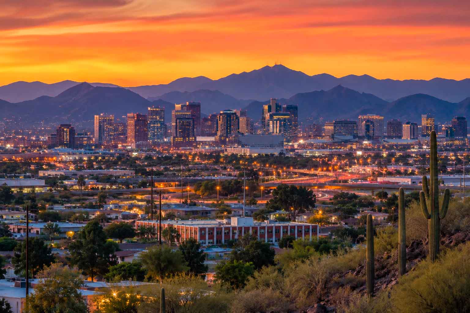 Phoenix skyline at dusk with desert landscape, city lights, and mountains in the distance, used as a regional context image for data center photographer services.
